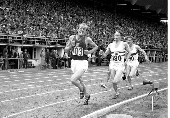 Emil Zátopek leading the 5000 m final at the 1952 Olympics in Helsinki, face contorted with effort, running to win after already claiming 10,000 m gold.